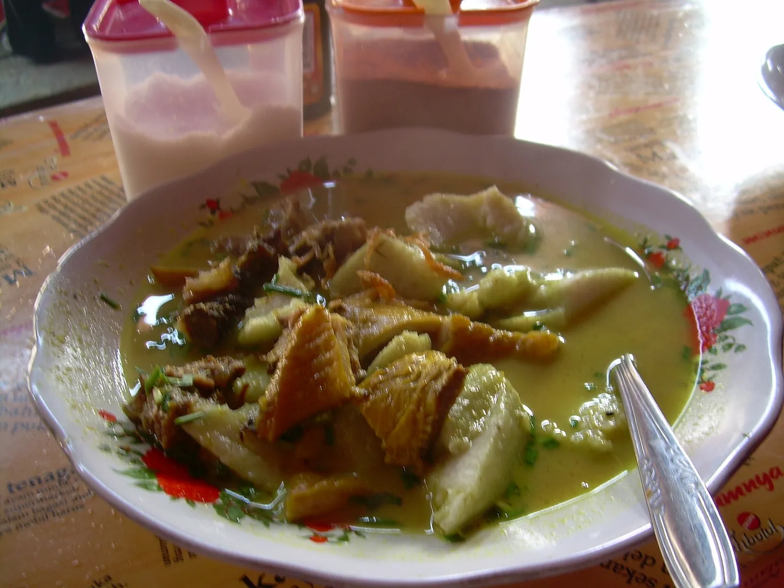 A bowl of empal gentong, yellow beef and tripe soup, on a restaurant table in Cirebon