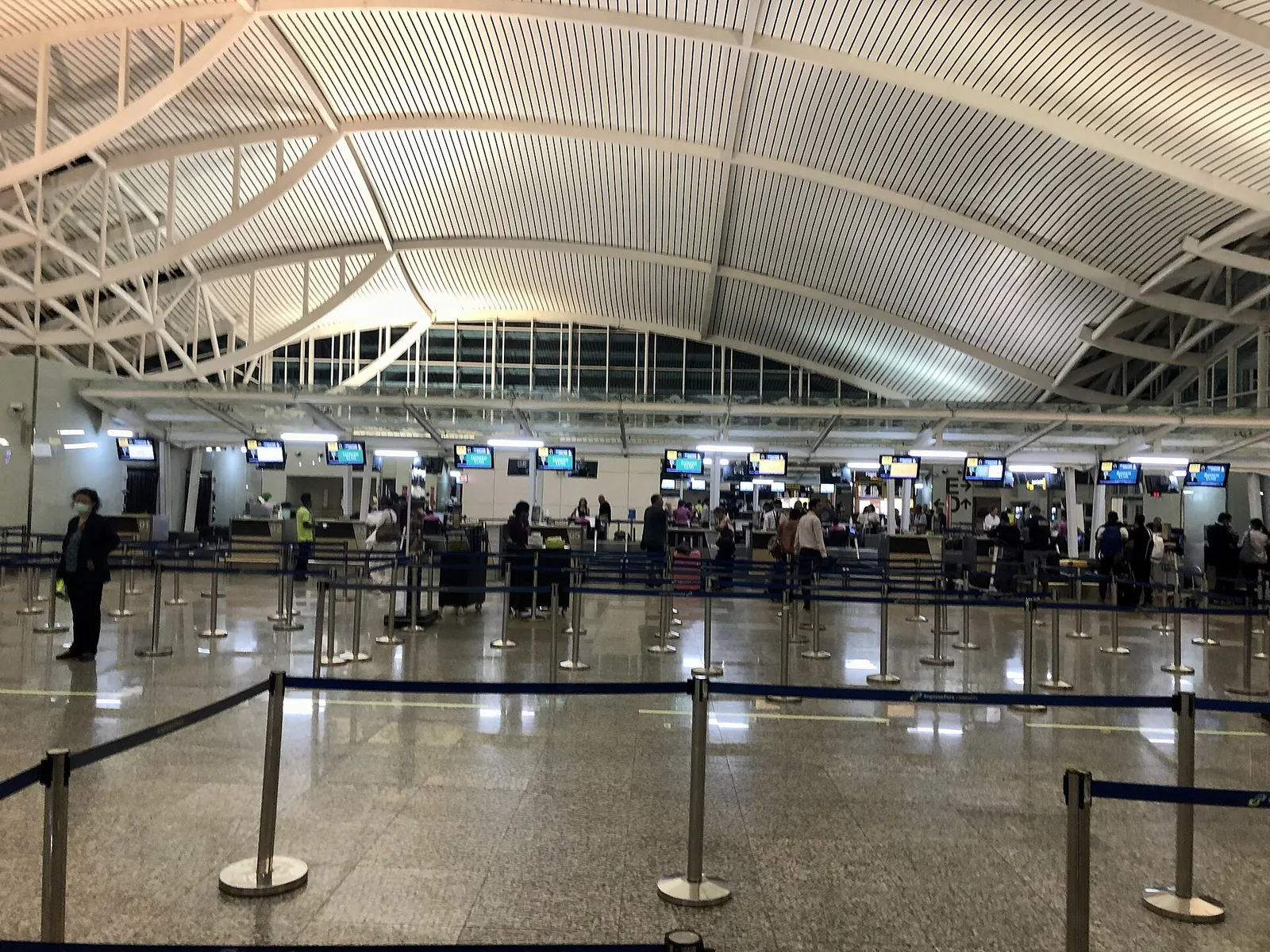 Immigration arrival hall with counters and queue lines under the curved roof of I Gusti Ngurah Rai International Airport, Bali