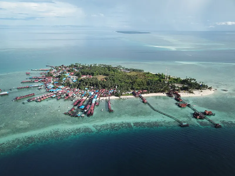 Aerial view of Derawan Island with its village, stilt houses and jetties over the shallow turquoise reef