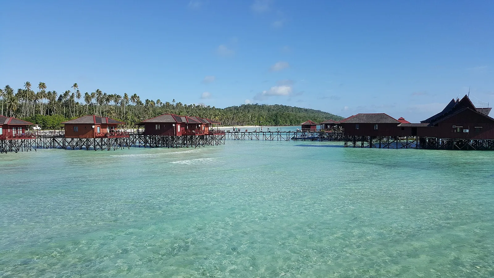 Wooden water chalets on stilts above a clear turquoise lagoon at Maratua Paradise Resort
