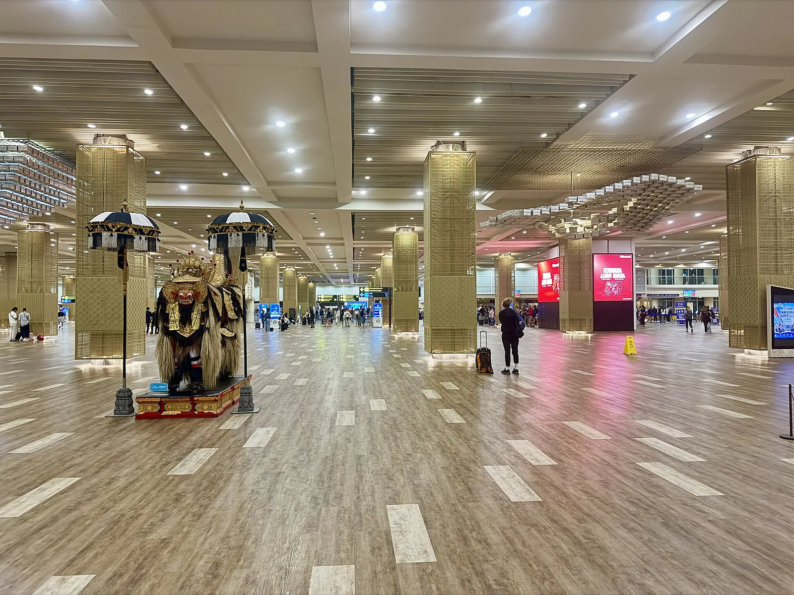 Wide hall with gold-clad pillars and a Balinese statue inside Ngurah Rai International Airport's international terminal
