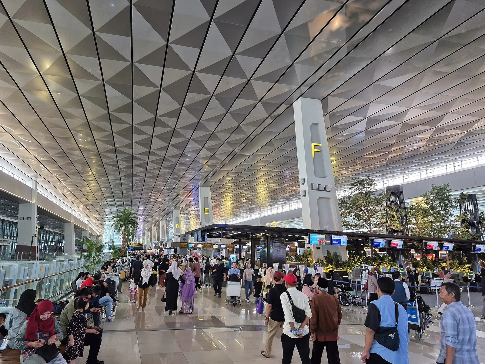 Busy check-in hall with a geometric ceiling at Soekarno-Hatta Airport Terminal 3 in Jakarta