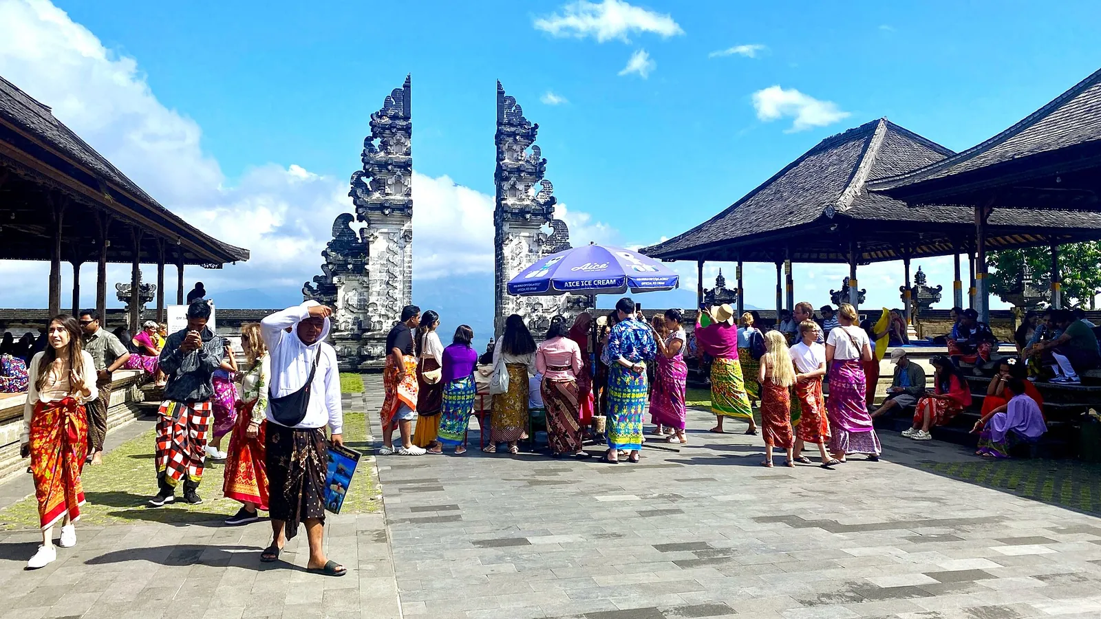 Visitors wearing sarongs and sashes in the front courtyard of Pura Penataran Agung Lempuyang in East Bali, beside the split gate