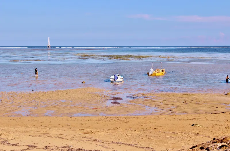 Shallow reef lagoon at low tide on Sanur Beach, Bali, with small pedal boats on the water