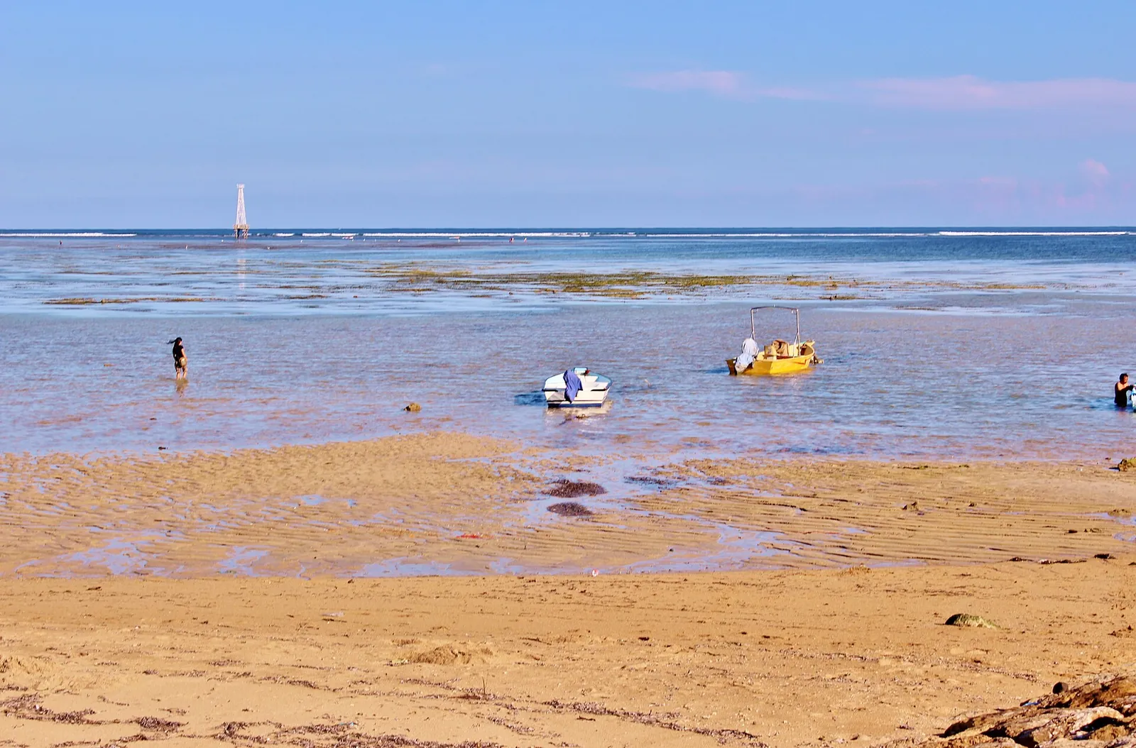 Shallow reef lagoon at low tide on Sanur Beach, Bali, with small pedal boats on the water