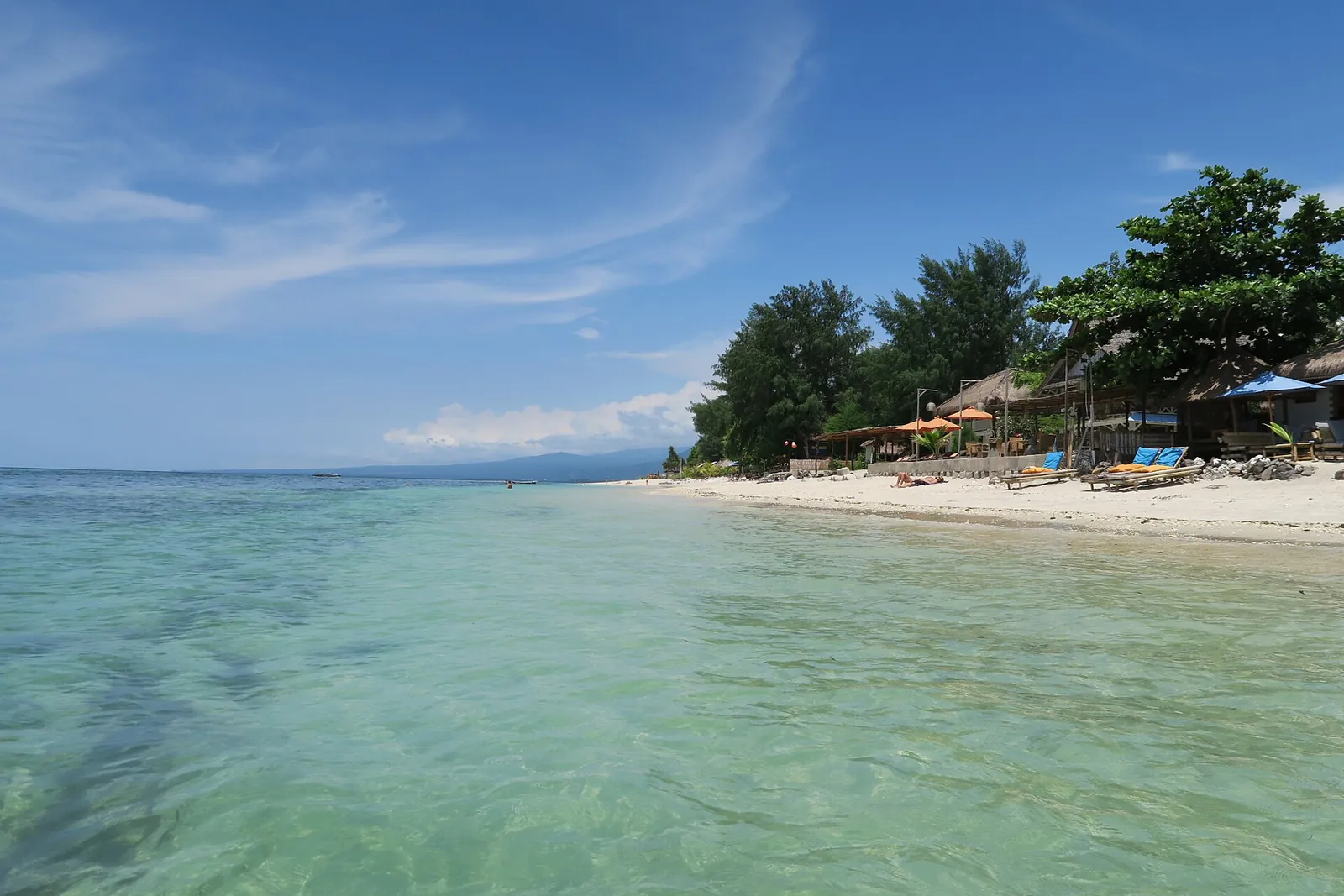 Clear turquoise water and a white-sand beach lined with trees on Gili Air