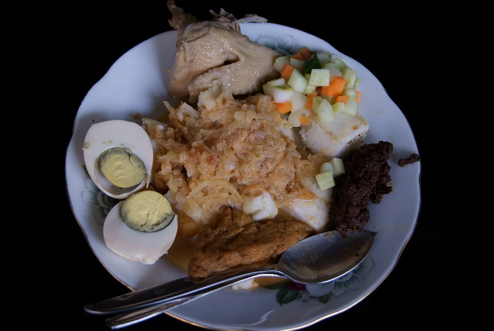 A plate of ketupat rice cake with opor ayam, pindang eggs, braised tofu, young papaya, pickles and rendang