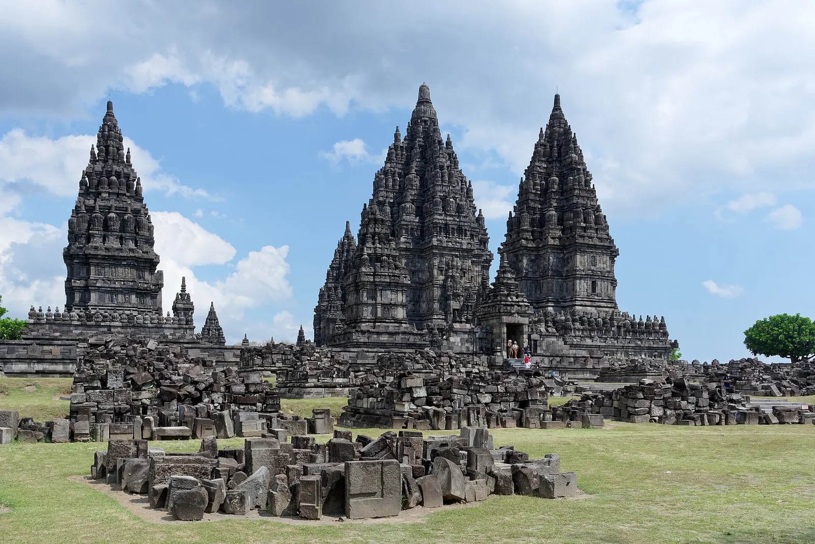 The tall stone spires of Prambanan temple in Central Java rising above fields of fallen temple blocks