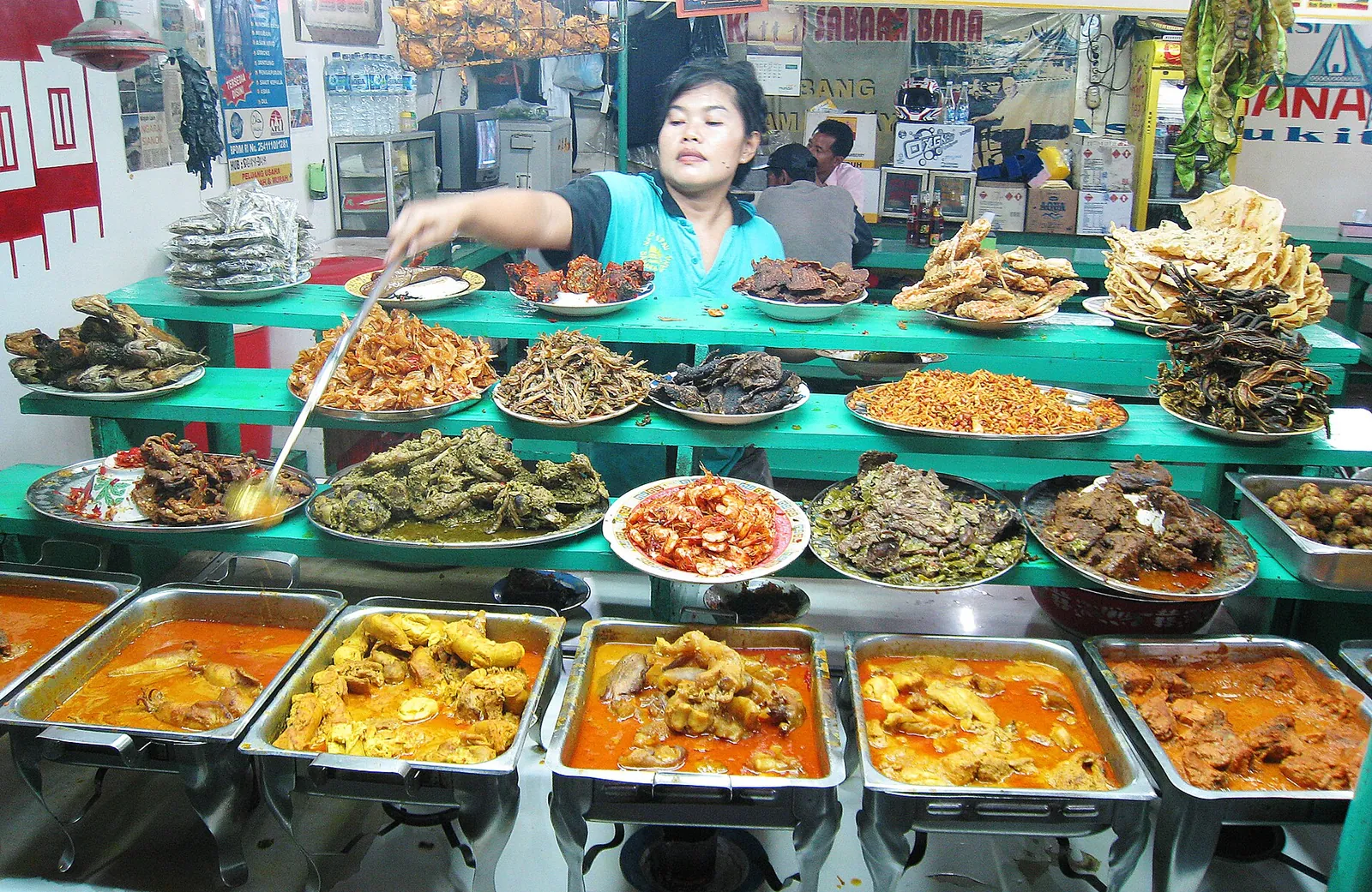 Rows of Minangkabau curries, fried fish and vegetable dishes stacked on a nasi kapau stall counter