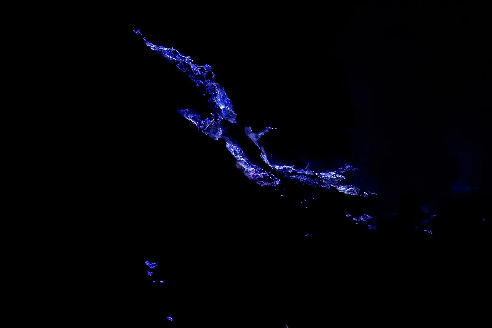 Streaks of blue flame burning in the darkness inside the Ijen crater