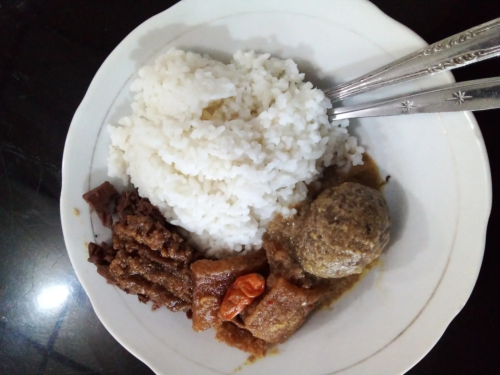 A plate of nasi gudeg: white rice with brown jackfruit stew, egg and side dishes