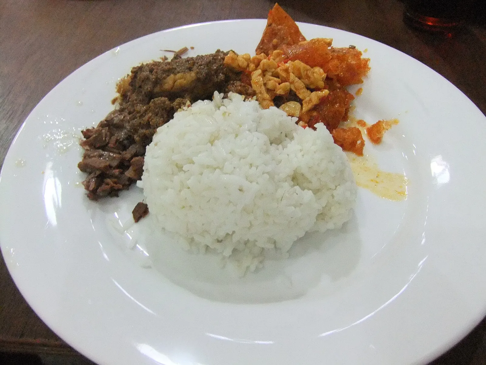 A plate of gudeg from Wijilan: white rice, dark slow-cooked jackfruit and orange, chilli-red krecek