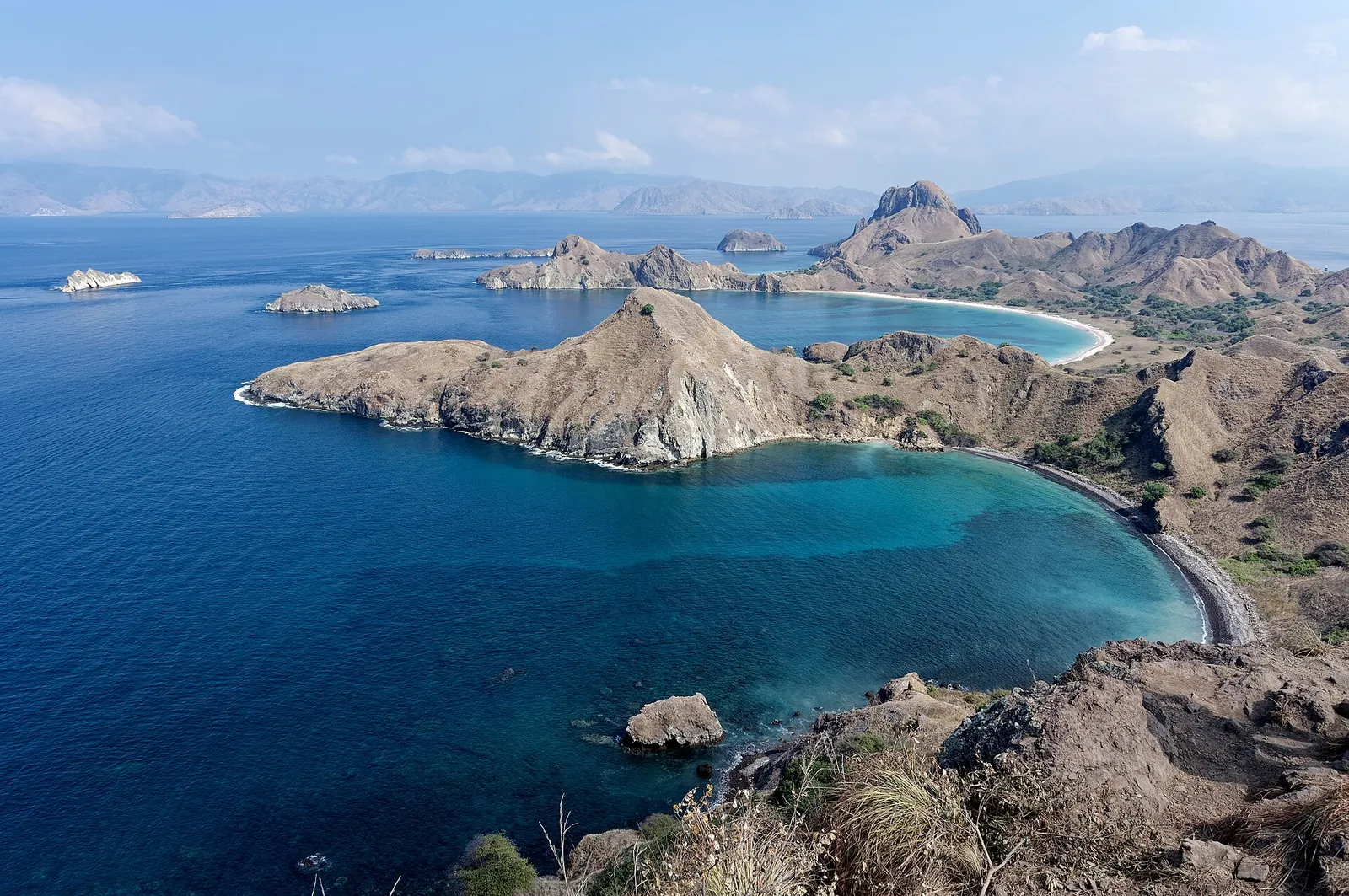 Padar Island's curved bays seen from the ridge viewpoint, with turquoise water and brown hills