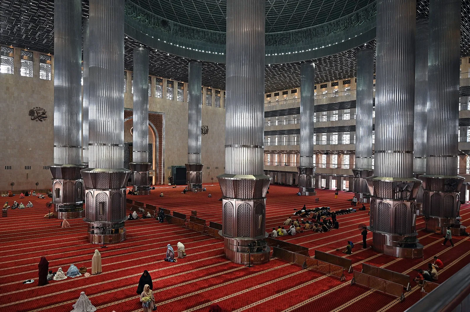 Rows of tall metal-clad columns and red carpet inside the main prayer hall of Istiqlal Mosque, Jakarta