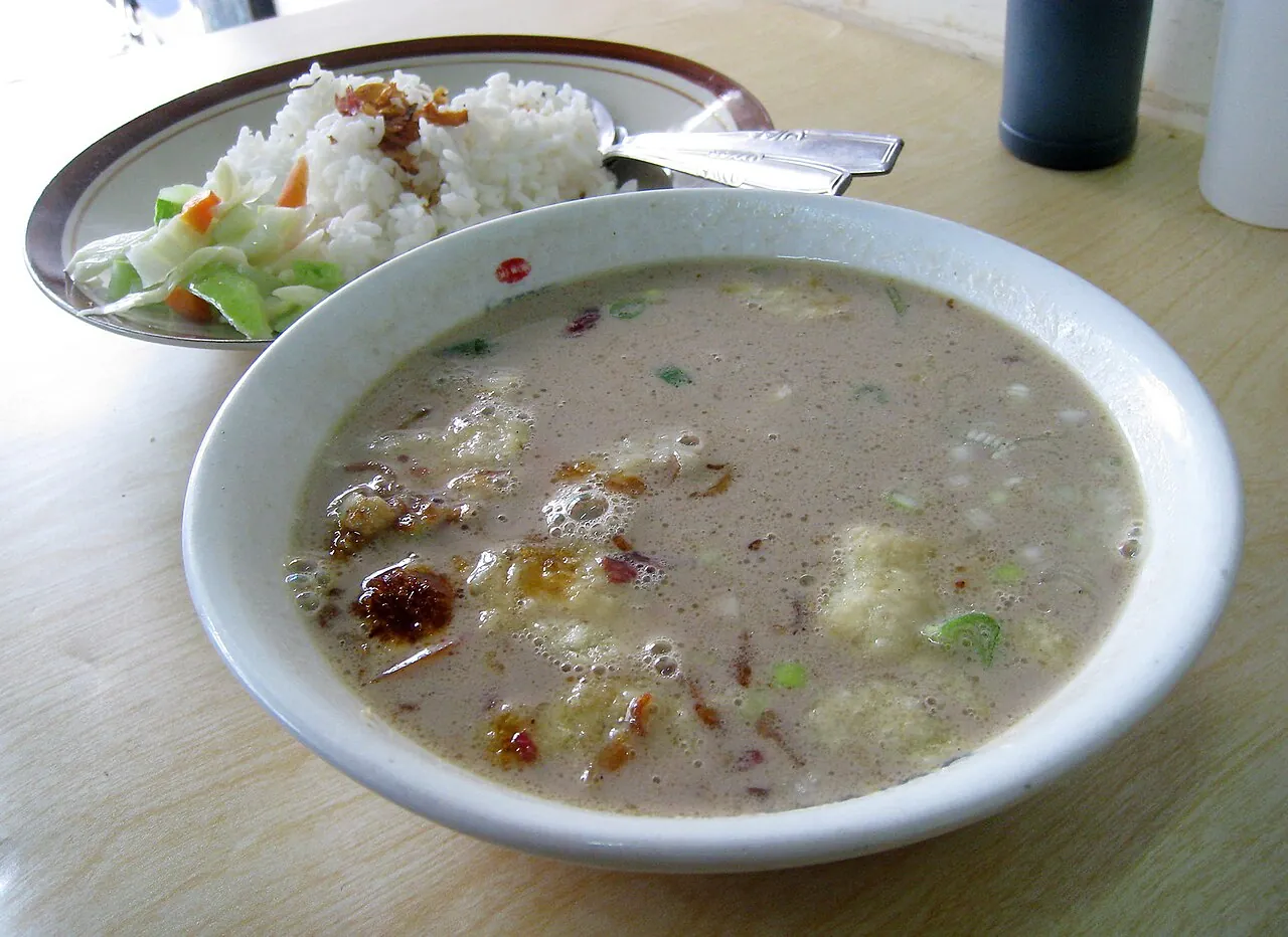 A bowl of soto Betawi, a pale, milky beef soup, served with a plate of rice at a Glodok warung