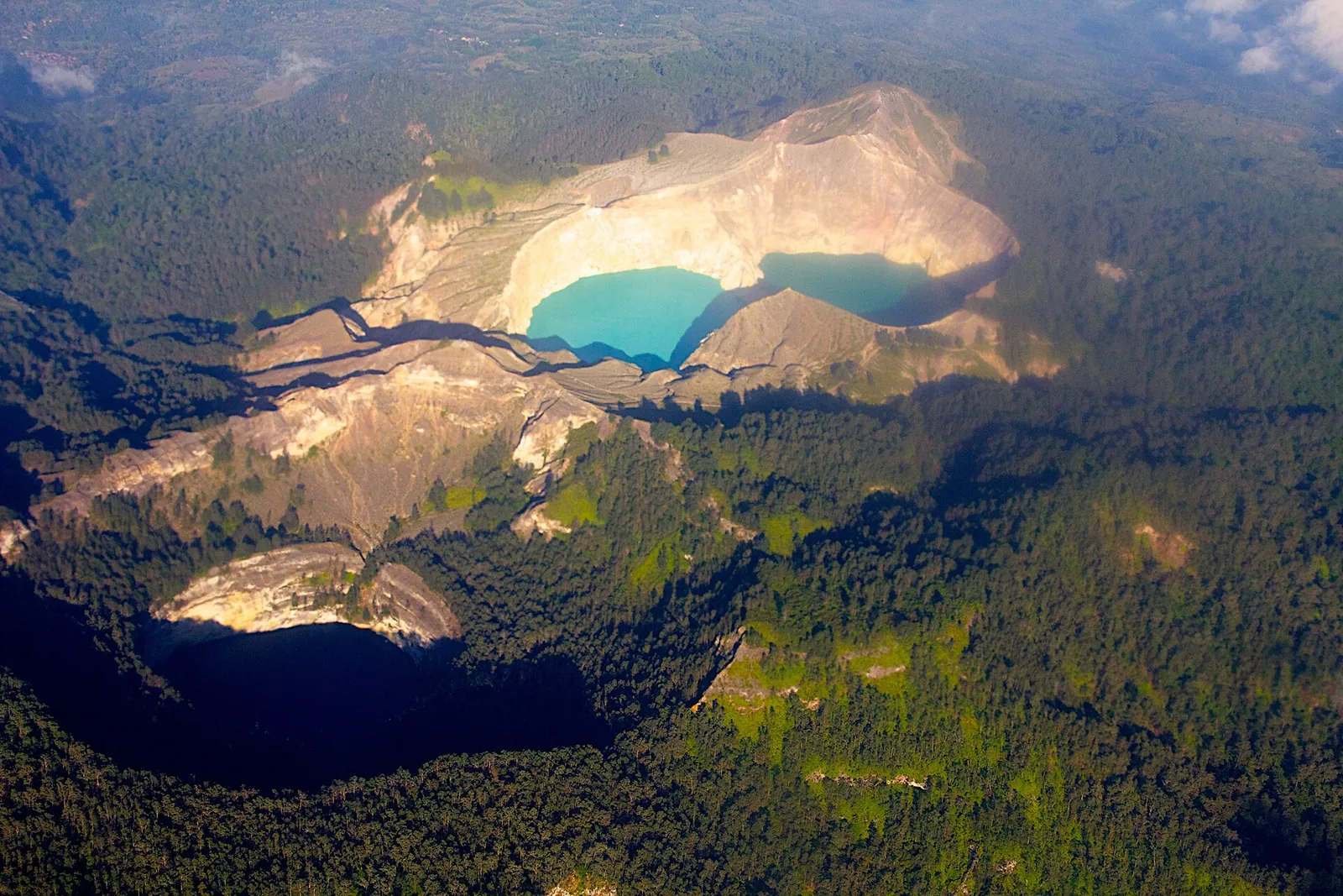 Aerial view of Kelimutu's summit with crater lakes set among forested slopes