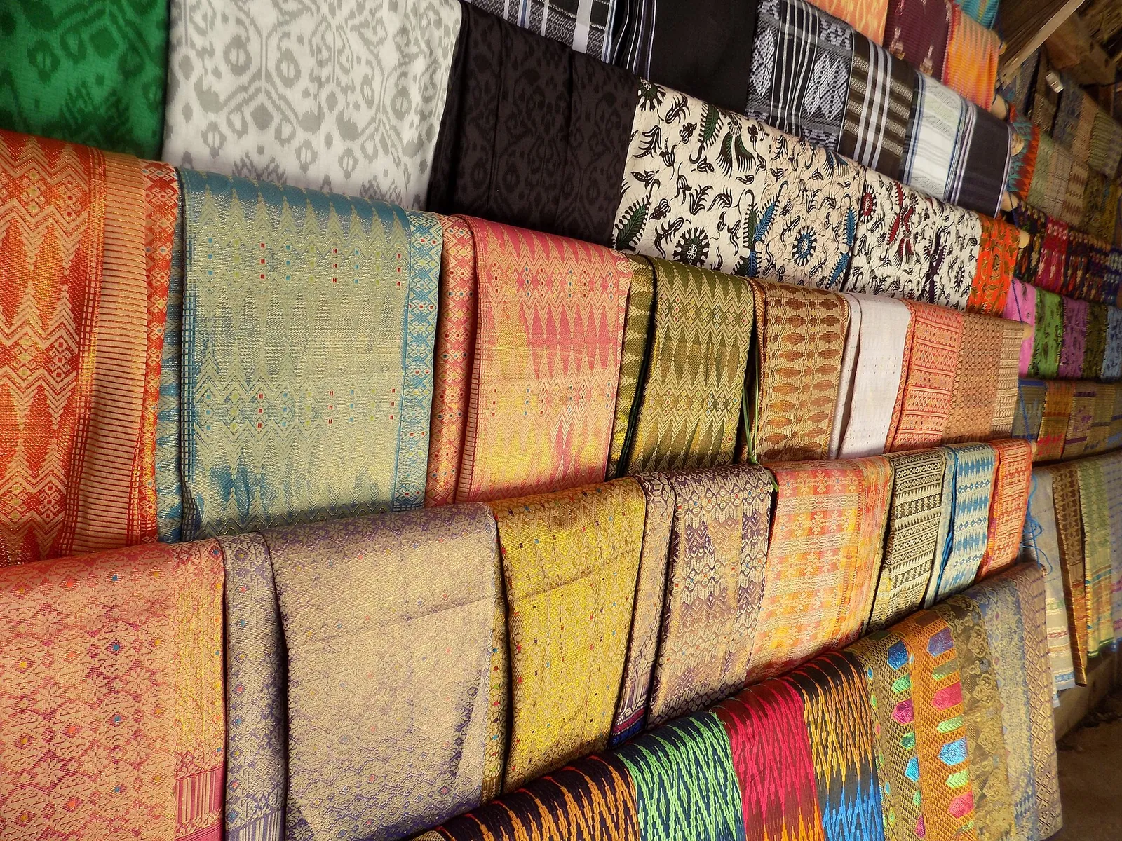 Stacks of hand-woven Lombok cloth in bright colours on display in Sade village