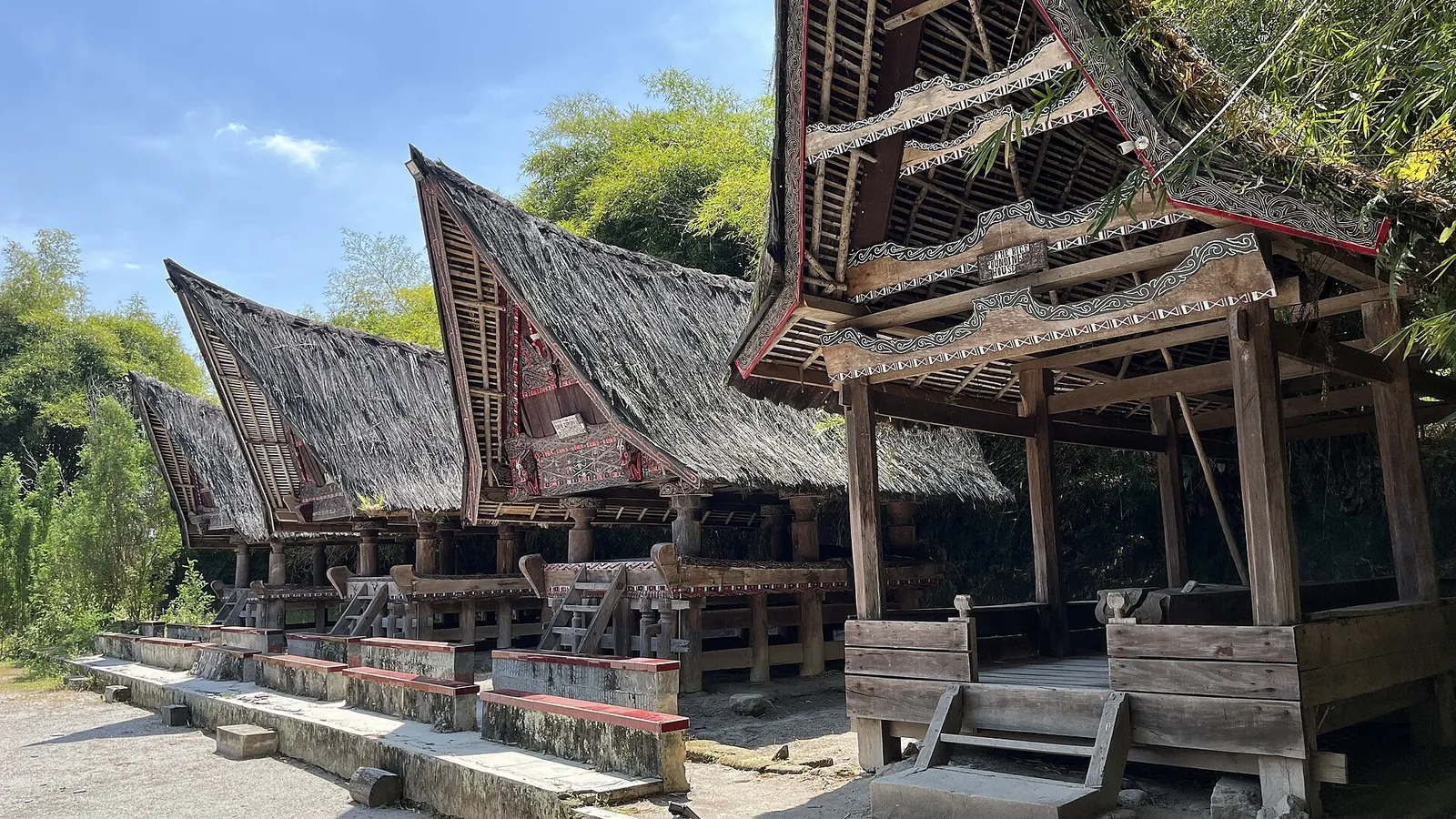 Row of Toba Batak houses with curved saddle roofs and carved gables at Museum Huta Bolon Simanindo