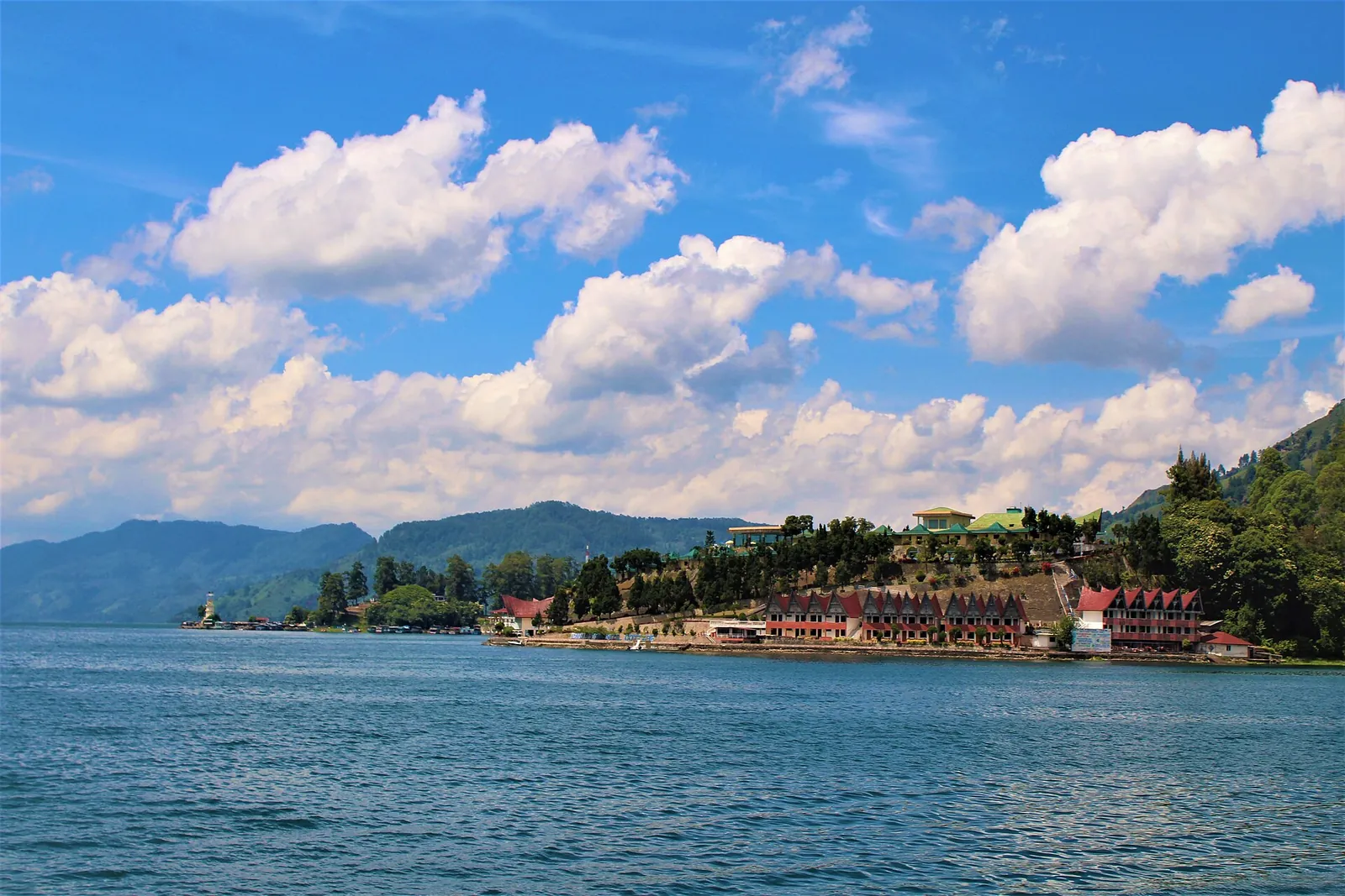Lake Toba under a cloudy blue sky with the lakeside town of Parapat on a headland