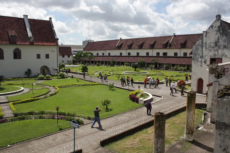 Lawns, paths and red-roofed Dutch colonial buildings inside Fort Rotterdam, Makassar, under a blue sky