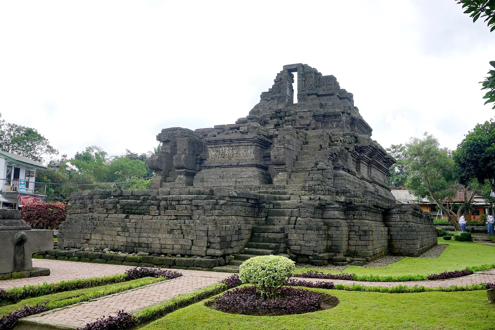 The terraced stone base of Candi Jago with a lawn and flower beds in front