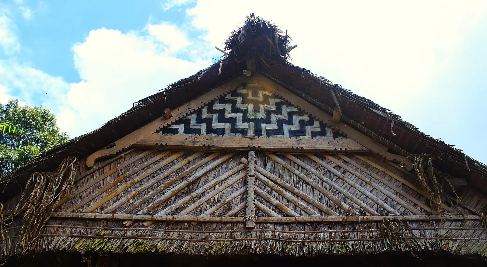 The thatched gable of a traditional Mentawai uma longhouse with a woven zigzag panel
