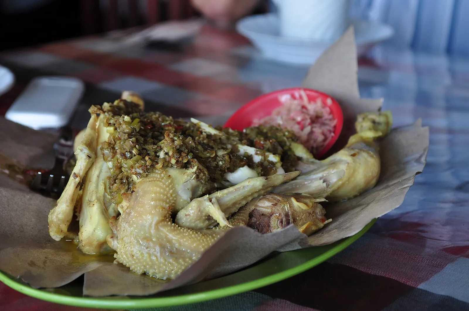 Whole ayam betutu chicken coated in yellow spice paste, served on banana leaf with sambal