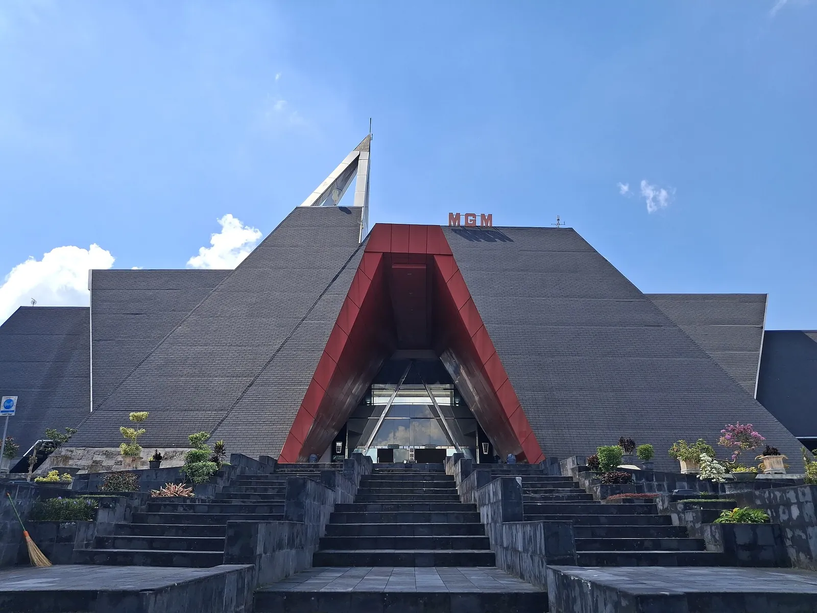 The grey, pyramid-shaped Merapi Volcano Museum building with a red entrance and front steps