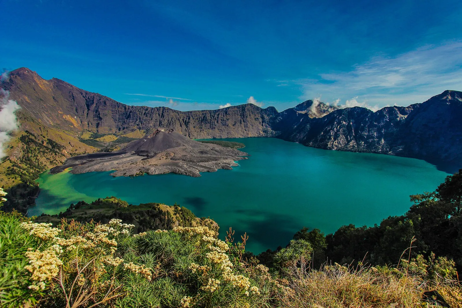 Turquoise Segara Anak crater lake with the dark Barujari cone, seen from the Mount Rinjani crater rim