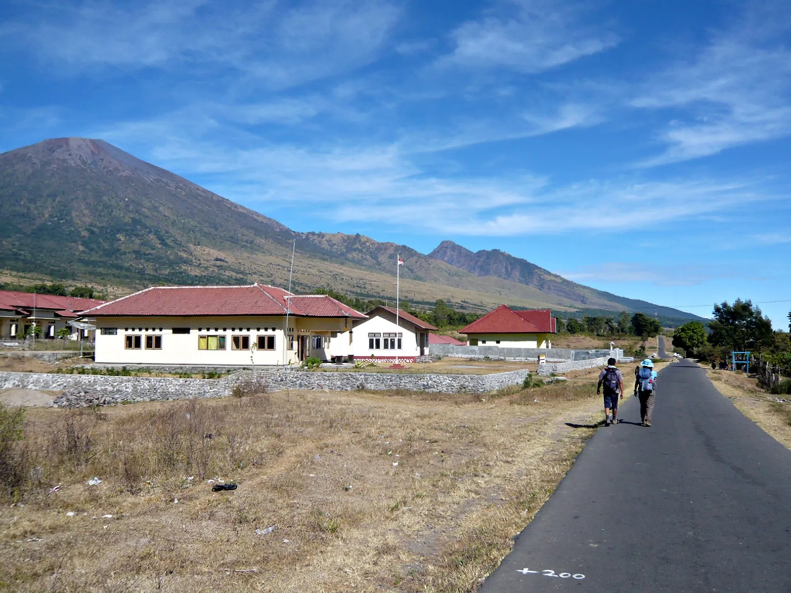 Road through Sembalun Lawang with Mount Rinjani behind under a blue sky