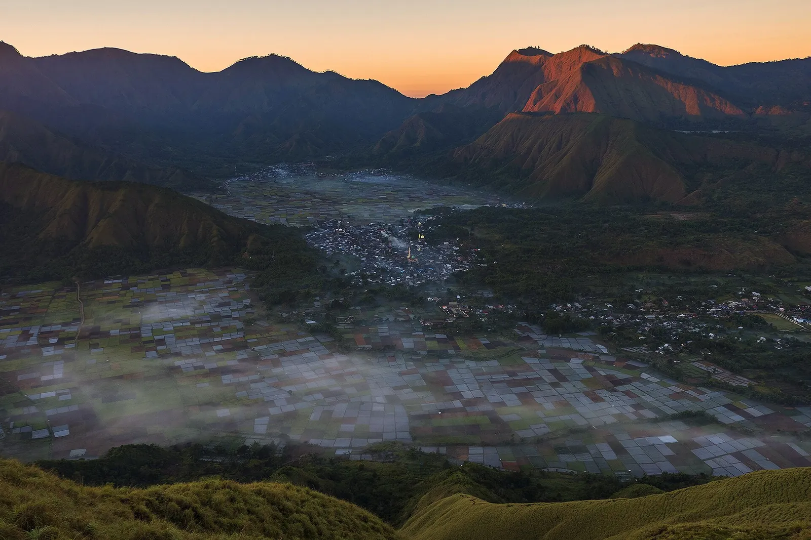 Sembalun valley farmland and village at dusk, ringed by mountains