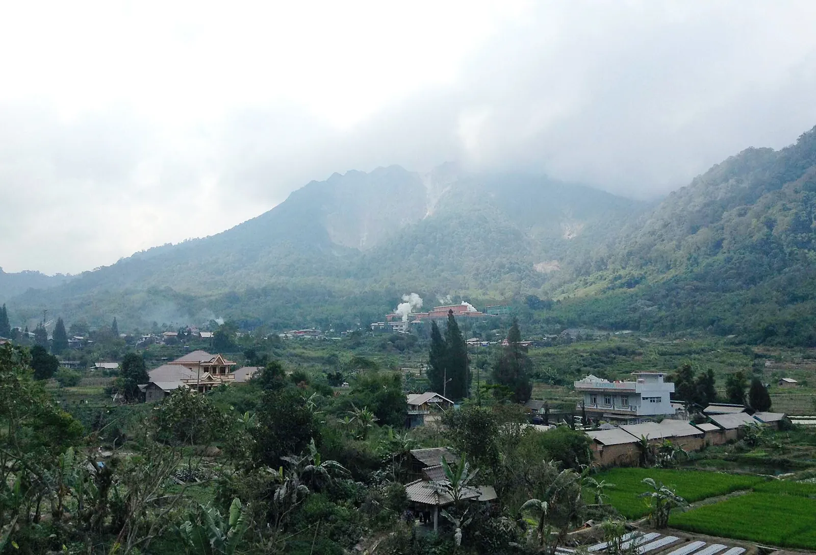 Mount Sibayak's grey crater flanks above the houses and gardens of Semangat Gunung village, Karo highlands