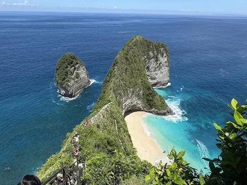 Plaża Kelingking na Nusa Penida widziana ze szczytu klifu, zielony przylądek nad łukiem białego piasku i turkusowym morzem