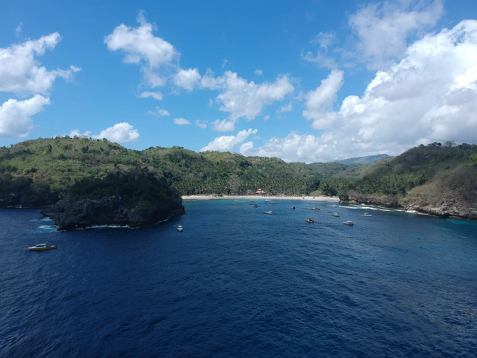 Crystal Bay on Nusa Penida from the water, a sheltered bay with boats, a white beach and a rocky islet