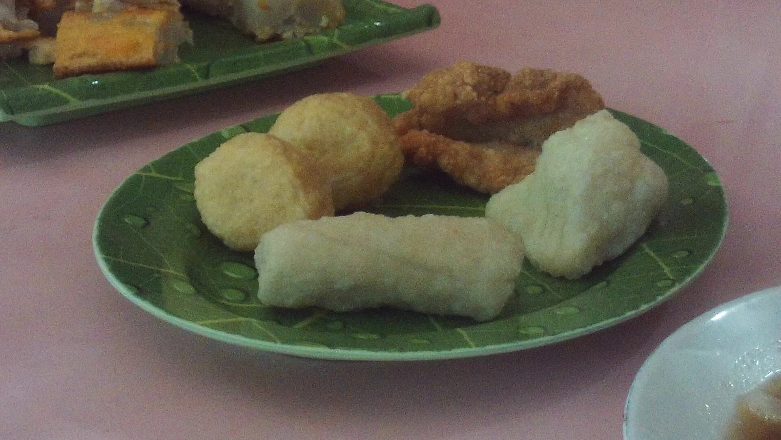 A plate of mixed pempek fish cakes, including a long lenjer and round pieces, at Pempek Saga Sudi Mampir in Palembang