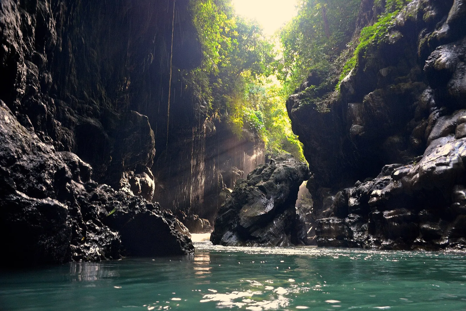 Green river water between dark, moss-streaked rock walls inside the Green Canyon gorge