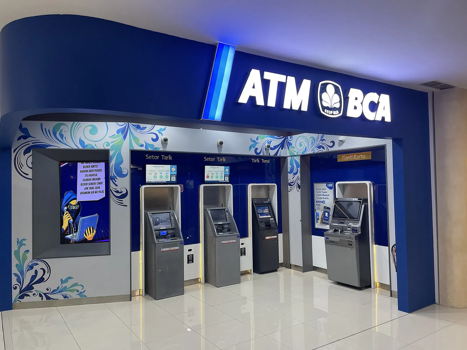 A row of blue-branded BCA cash machines in a terminal hall at Bali's Ngurah Rai Airport