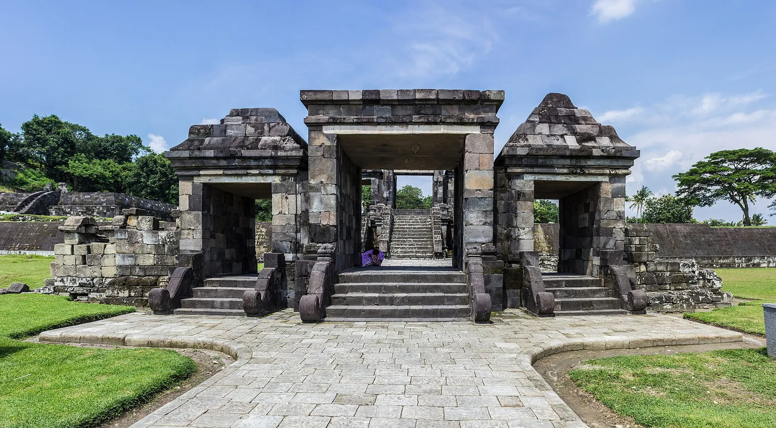 The stone gateway of Ratu Boko at the top of a paved path between lawns