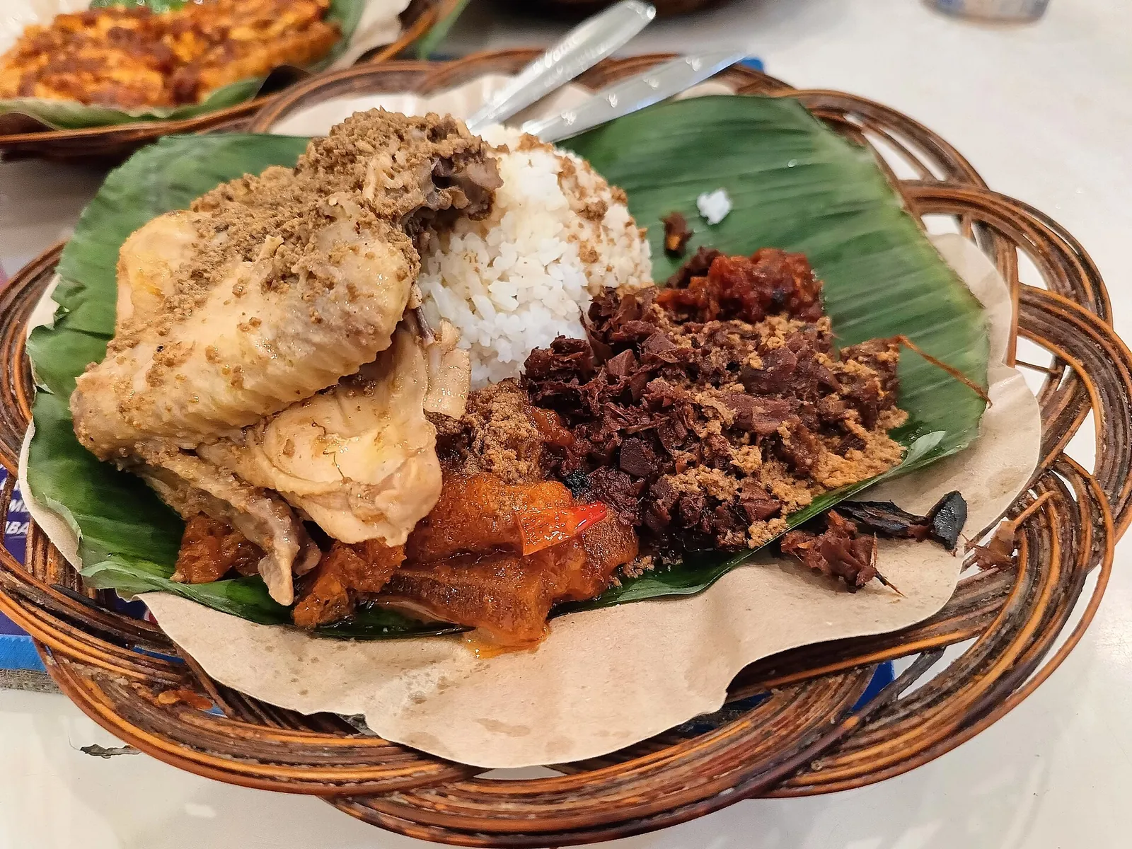 A plate of gudeg with chicken, rice and sambal krecek on a banana leaf