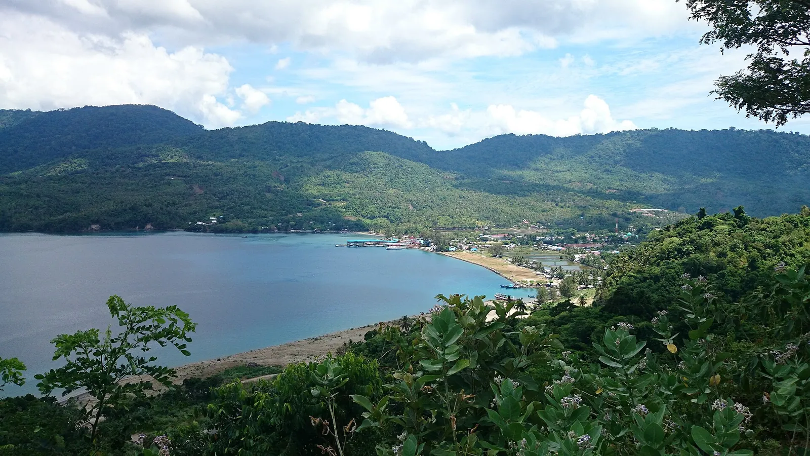View from a hill over Balohan bay and port on the east side of Pulau Weh, with green hills behind