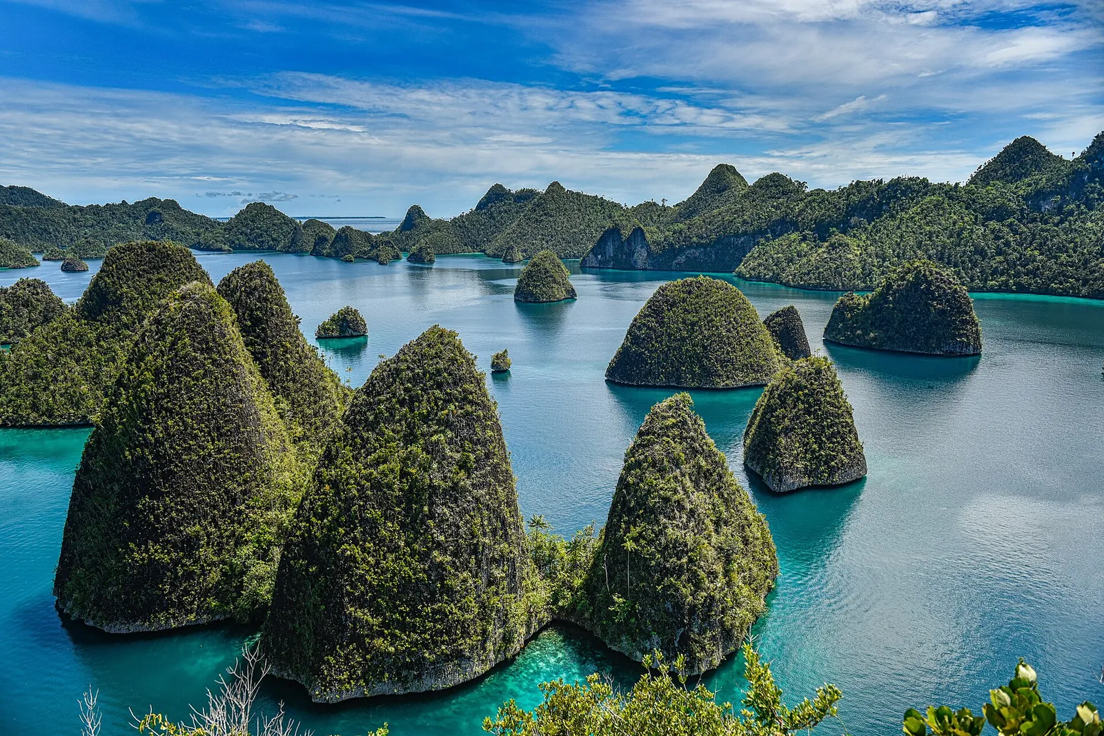 Cone-shaped forested karst islands rising from blue water at Wayag, Raja Ampat