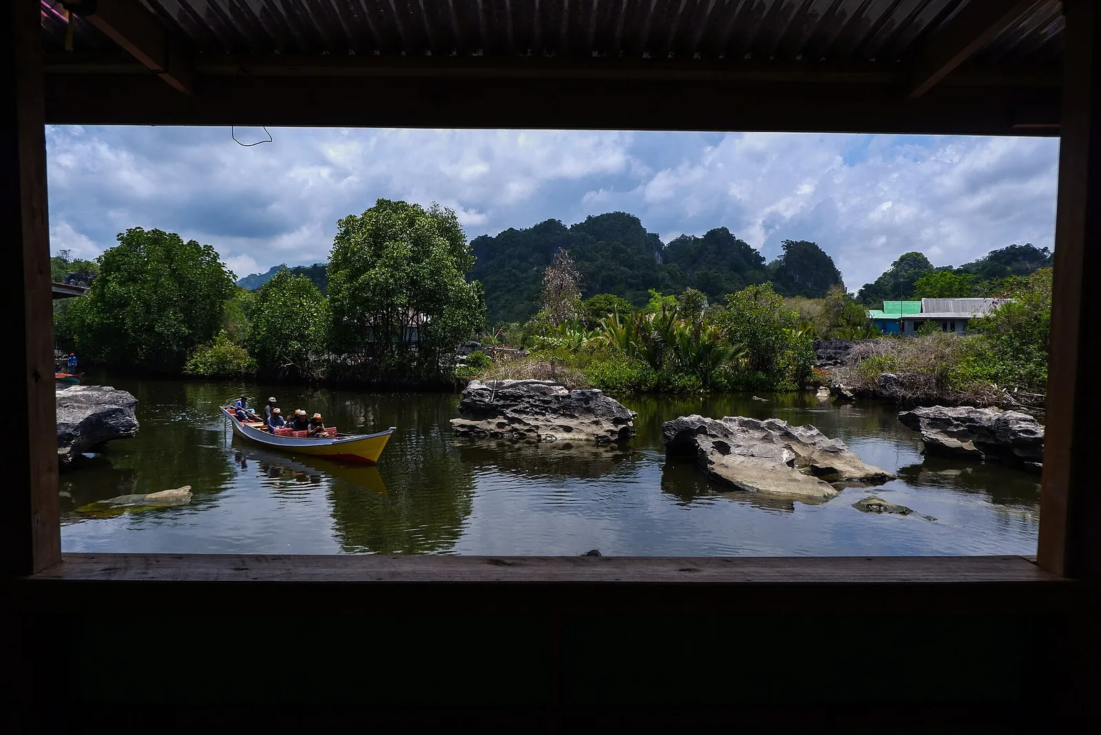 View from a wooden shelter over the river and rocks to the karst hills at Rammang-Rammang, with a boat moored