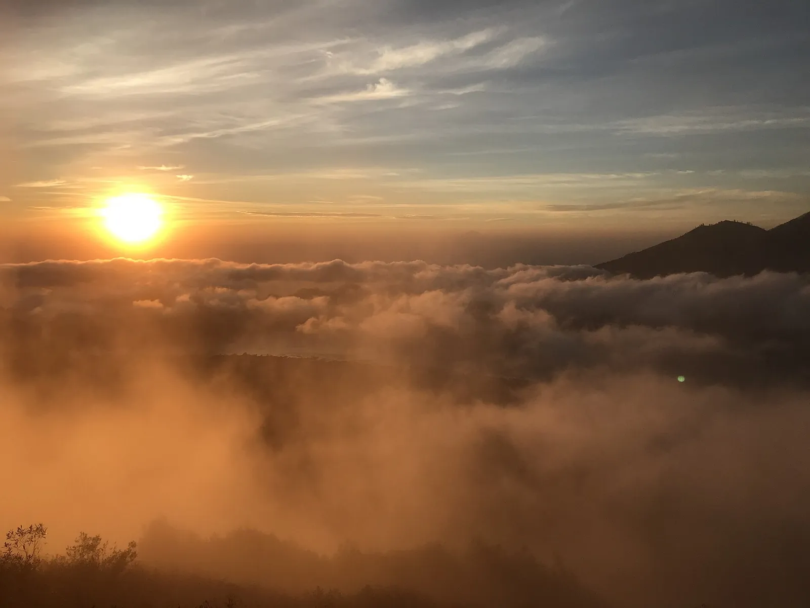 Sun rising over a sea of cloud seen from the summit of Mount Batur in Bali