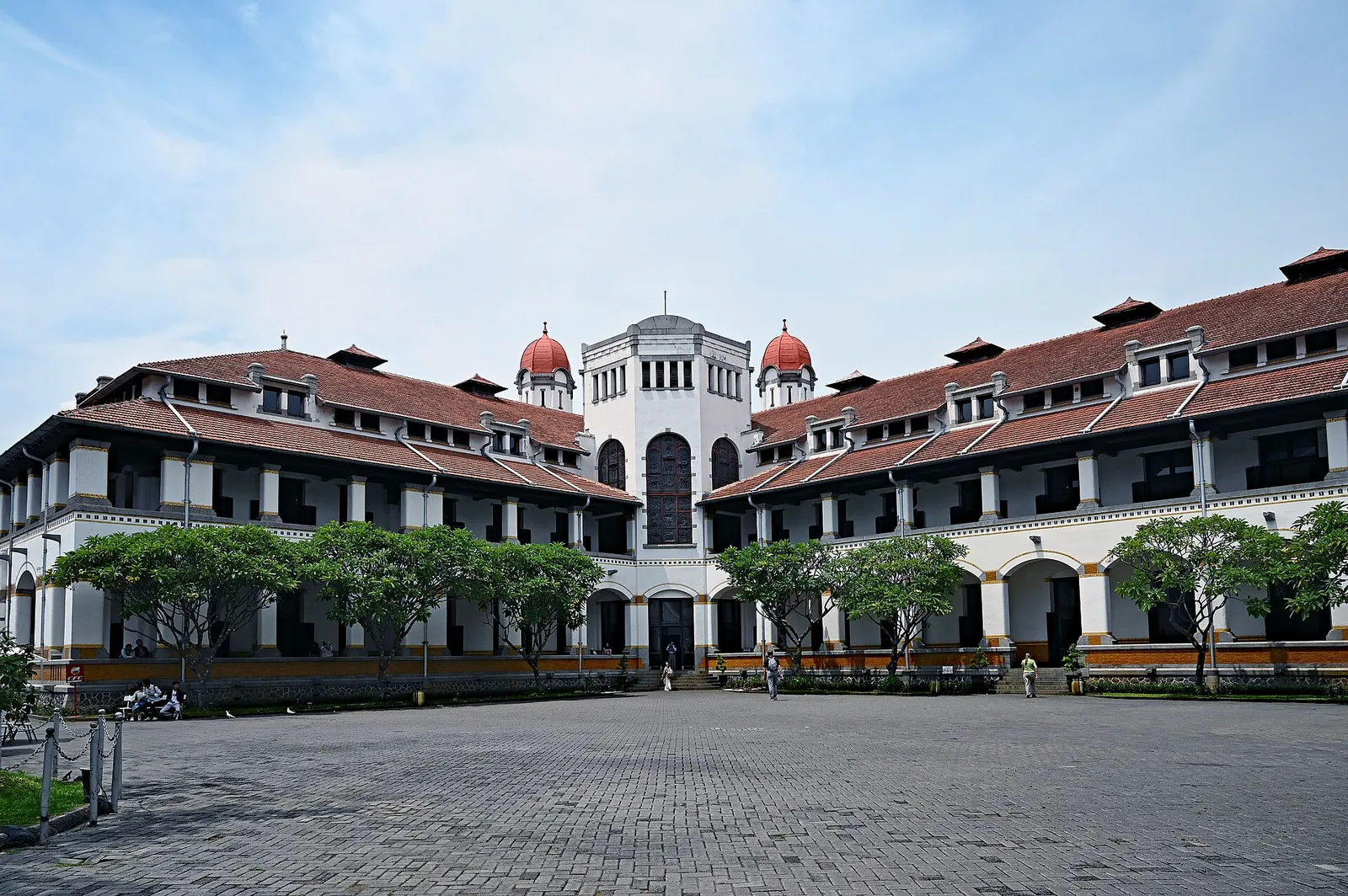 Lawang Sewu's long white colonial wings with red-tiled roofs around a paved courtyard in Semarang