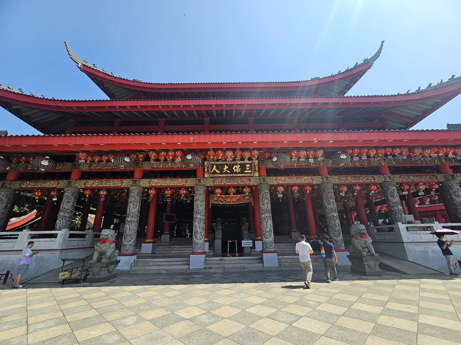 Red-pillared main hall of Sam Poo Kong temple with tiered curved roofs and stone lions at the steps