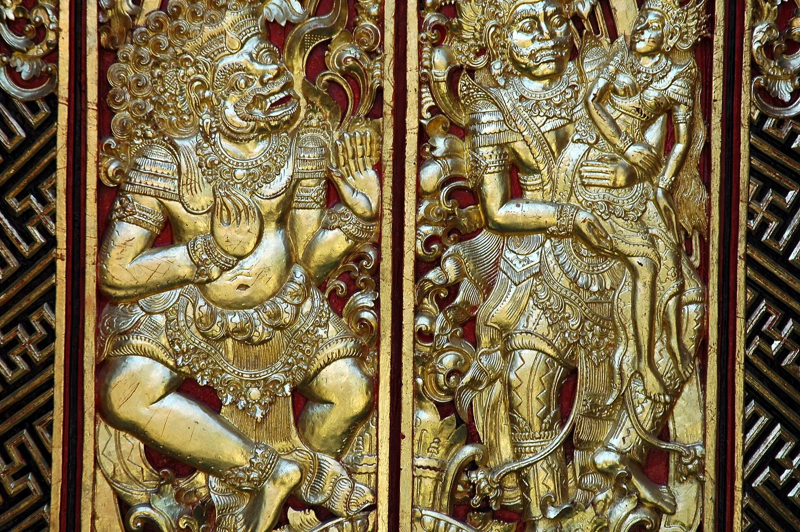 Gilded carved wooden temple doors with Balinese guardian figures at Pura Petitenget