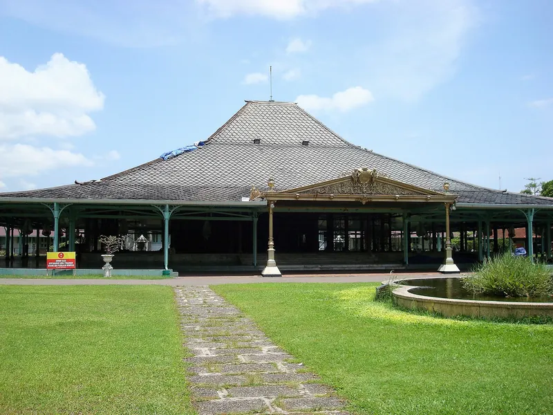 The great timber pendopo of the Pura Mangkunegaran in Solo under a blue sky, with a lawn and path in front