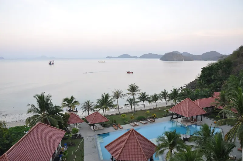 Bungalows d’hôtel aux toits de tuiles rouges et piscine au-dessus de la baie de Labuan Bajo, Flores, îles à l’horizon