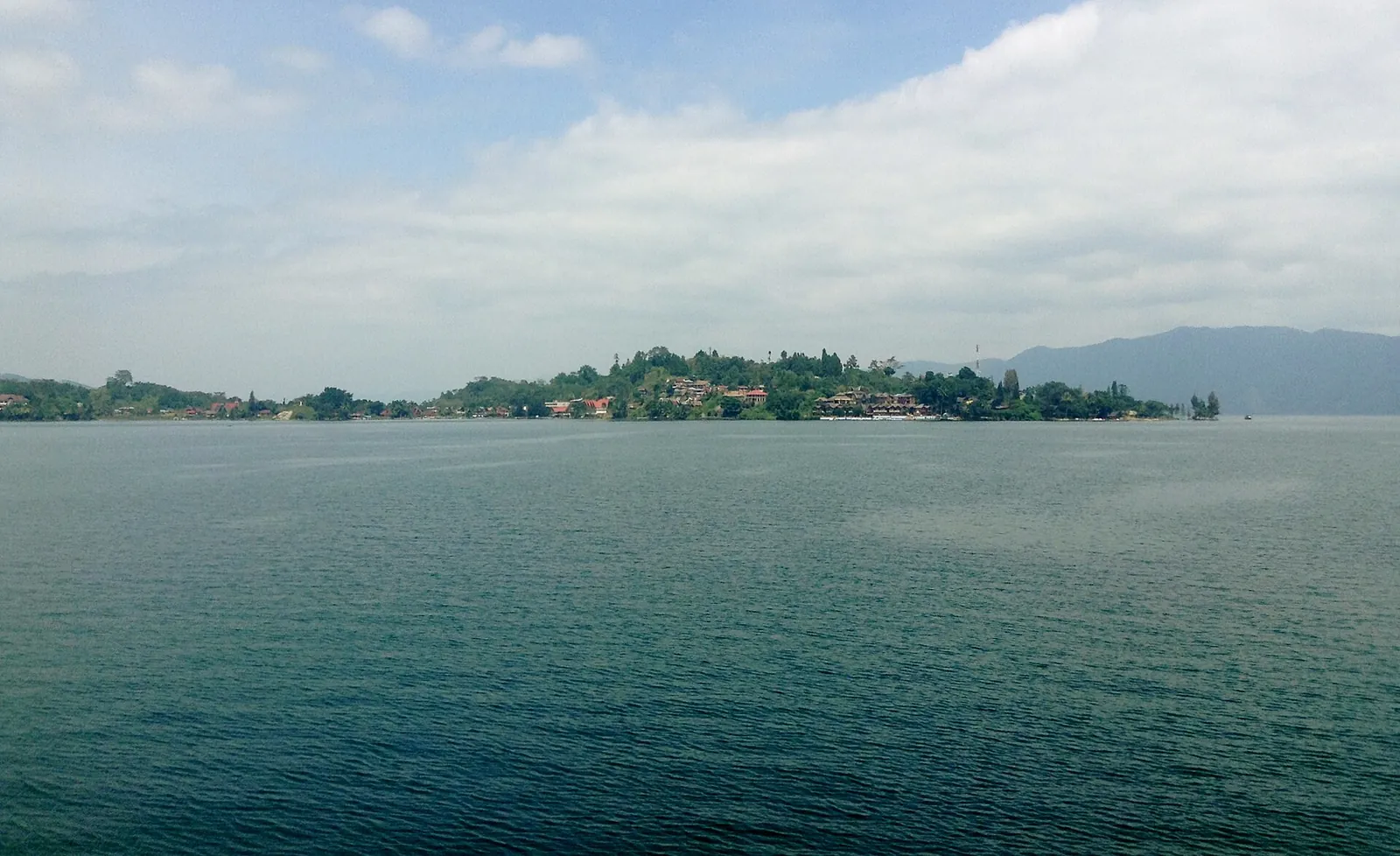 Hotels and guesthouses along the shore of the Tuktuk peninsula on Samosir Island, seen across Lake Toba