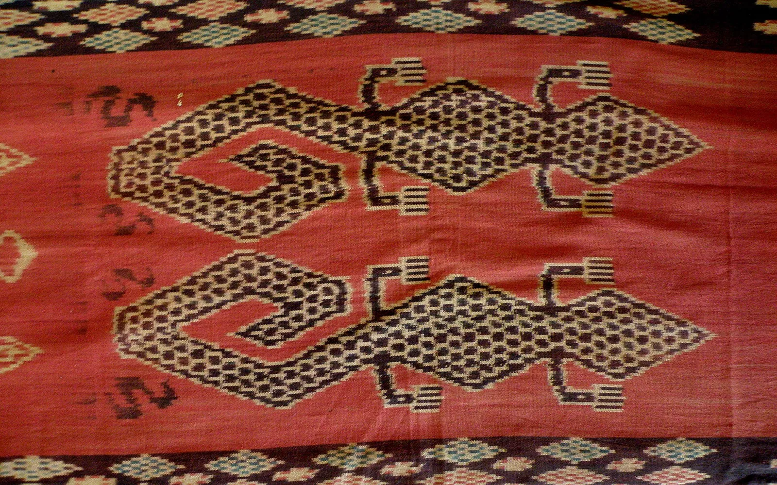 Close-up of a red Sumba hinggi ikat cloth with a large patterned gecko motif